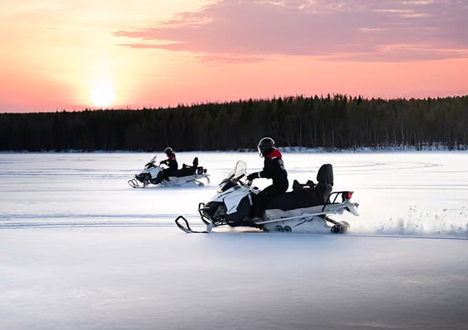 Kaksi naisvierasta ajamassa moottorikelkalla Palojärvellä Aito Resortissa