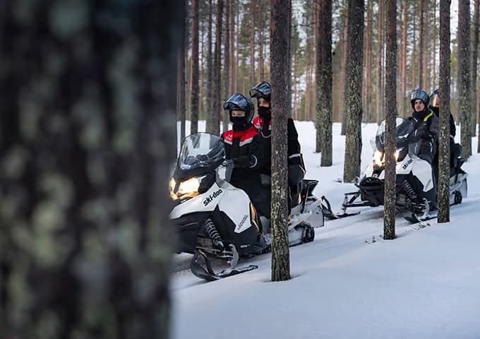 Group of Aito Resort guests snowmobiling through a forest