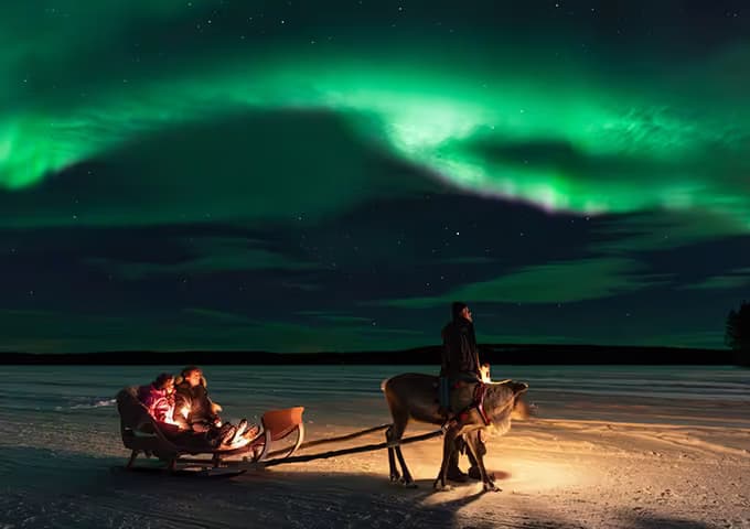 Guests enjoying a reindeer sleigh ride under the Northern Lights at Aito Resort
