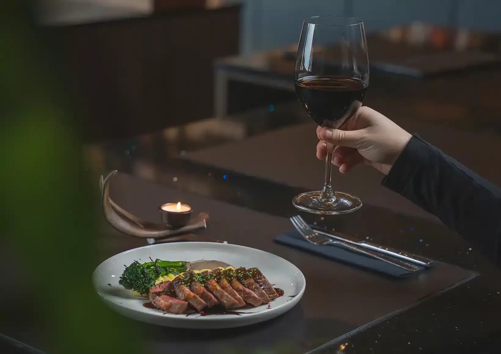 Plated main course and a glass of red wine at Wildwoods Restaurant