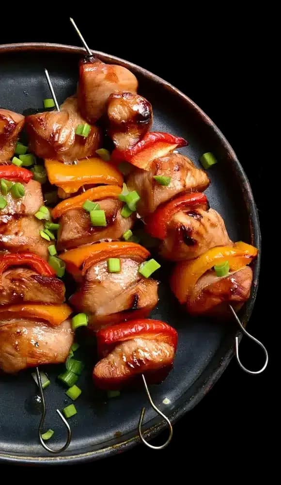 Grilled meat and vegetable skewers on a dark plate