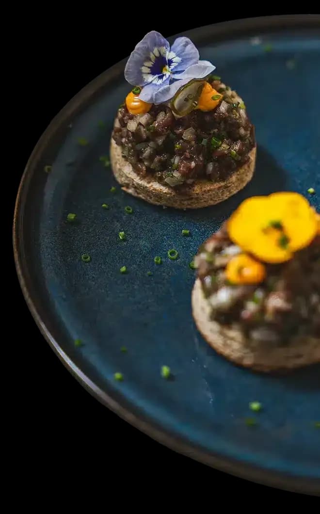 Reindeer tartare canapés garnished with an edible flower