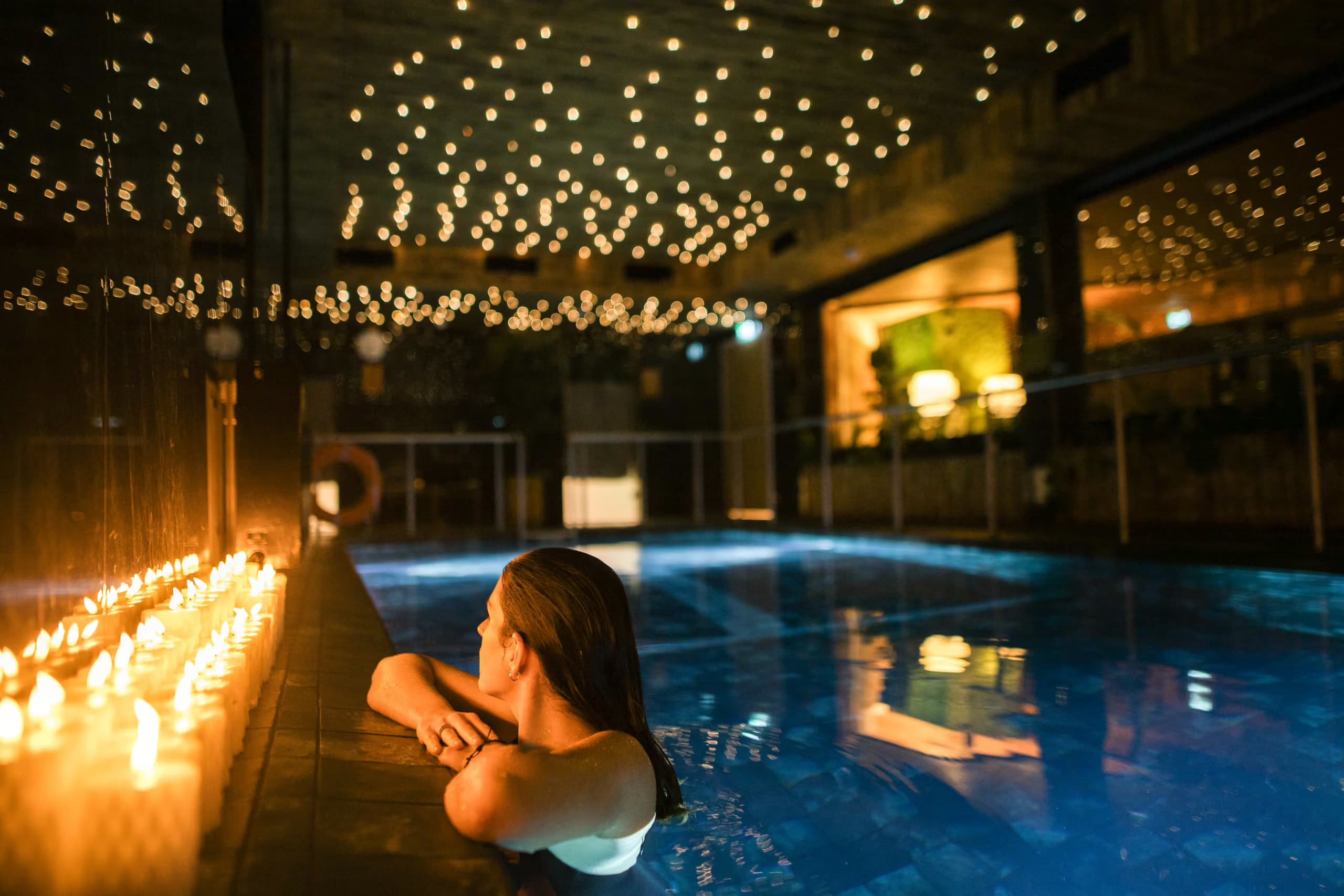 Woman relaxing in a candle-lit vitality pool at Aito Resort
