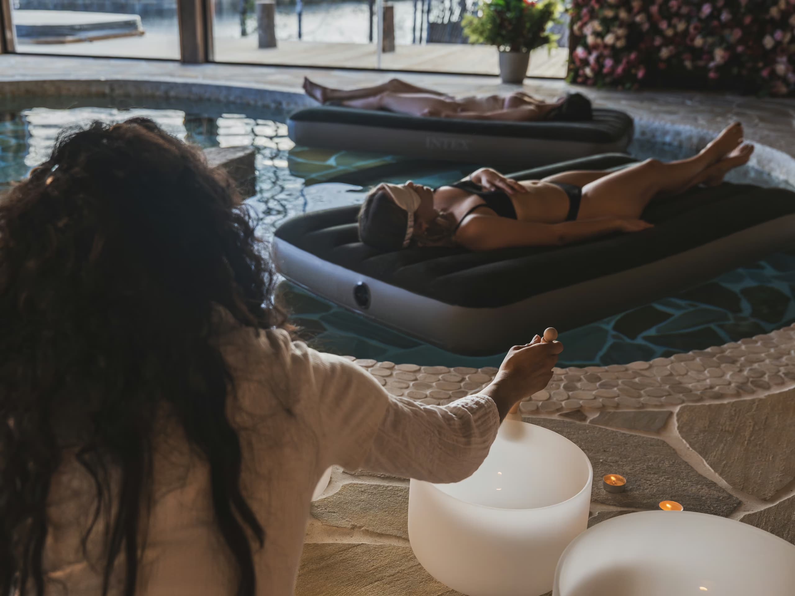 Guest floating in a pool while a therapist plays crystal singing bowls at Aito Resort Arctic Spa Centre